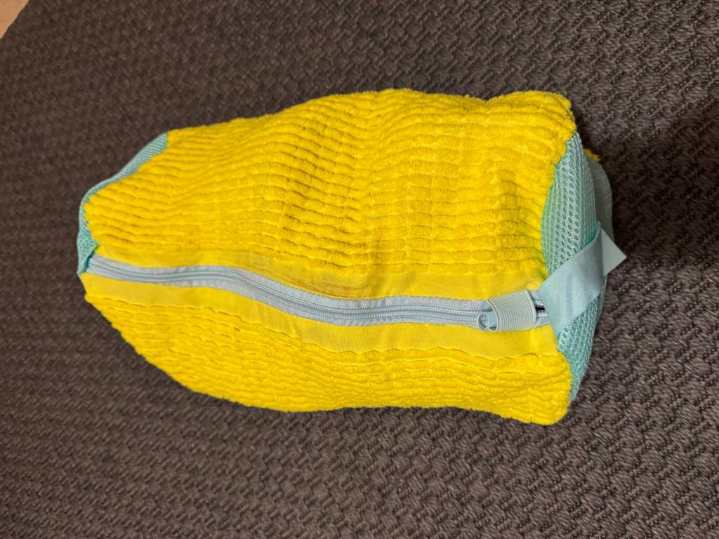 Μία κίτρινη τσάντα πλυντηρίου για παπούτσια με μπλε φερμουάρ.